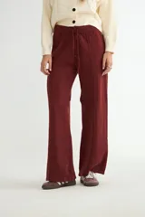 Pantalón de punto color crema, de corte recto y holgado, con cintura elástica y cordón ajustable. Presenta costuras verticales decorativas a lo largo de las piernas.