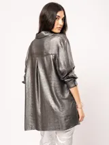 Camisa oversized con terminación metalizada color gris plomo. Tiene botones a tono en el delantero, largo por debajo de la cadera y tajos a los costados.