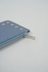 Billetera pequeña color negro con cierre de cremallera plateado y apliques de tachas metálicas redondas en la parte frontal.