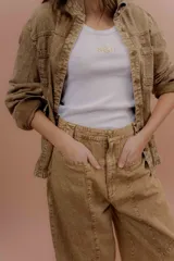 Musculosa básica de tejido acanalado color blanco, con escote redondo, calce al cuerpo y el logo NSLD bordado en el centro del frente.