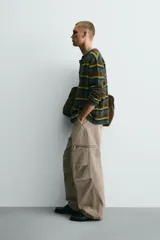Pantalón cargo de corte relajado con efecto lavado, confeccionado en tejido de algodón. Presenta bolsillos frontales, bolsillos traseros con solapa y bolsillos con cierre de cremallera en las perneras. Incluye pliegues en las rodillas y ajuste en los tobillos.