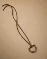 Gargantilla de cuero marrón con dije metálico en forma de argolla triangular.