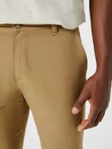 Pantalón tipo chino de corte slim, color beige, con cierre de botón y cremallera, y bolsillos laterales.