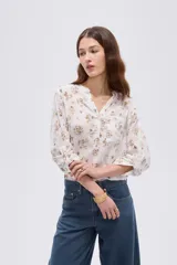 Blusa de viscosa color beige con cuello en V, cierre parcial de botones frontales, bolsillo en el pecho y mangas 3/4.