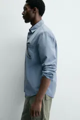 Camisa de corte relajado confeccionada en una mezcla de lyocell y algodón con efecto lavado. Presenta cuello solapa, manga larga con puños abotonados, bolsillo de plastrón en el pecho y cierre frontal con botones.