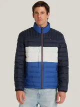 Chaqueta acolchada de diseño color block en tonos azul marino, blanco y azul brillante. Presenta cuello alto, cierre frontal con cremallera y bolsillos laterales con cierre. Incluye el logo de la marca bordado en el pecho y detalle distintivo en la manga.