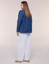 Sobrecamisa azul de denim de algodón liviano, con cuello camisero, cierre frontal de botones, bolsillos con solapa en el pecho y cordón ajustable en la cintura.