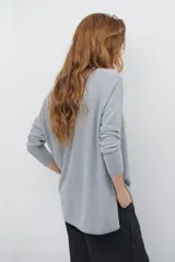 Sweater de tejido de punto color beige, con escote en V y mangas largas. Presenta un diseño básico y versátil de corte recto.