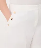 Bermuda de tiro alto confeccionada en crepé color blanco, con cierre frontal, bolsillos laterales y detalle de botones decorativos.