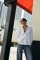 Camisa de algodón con diseño de rayas verticales sutiles, cuello solapa, manga larga con puños abotonados y cierre frontal con botones.