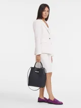 Bolso de mano tipo tote de la línea Le Roseau de Longchamp, confeccionado en cuero granulado negro. Presenta un diseño estructurado con asas superiores, correa de hombro ajustable y extraíble, y el icónico cierre de bambú metálico en la parte frontal.