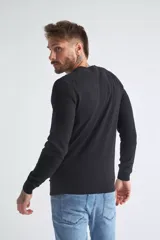 Sweater de tejido de punto color beige, con escote en V, mangas largas y puños y dobladillo acanalados. Presenta un pequeño logo bordado en el pecho.