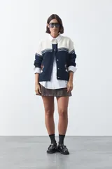 Cardigan de tejido jacquard en color azul marino y blanco, con diseño de conejitos en los laterales, cierre frontal con botones y cuello redondo.