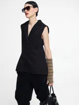 Chaleco sastrero negro con pinzas en la espalda, largo irregular y botones en la delantera.