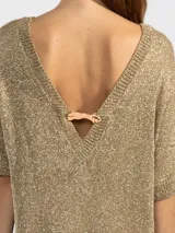 Vestido corto de punto con hilos metálicos que aportan un brillo sutil. Presenta un calce relajado, cuello redondo, mangas cortas y espalda en V pronunciada con detalle de dije metálico.