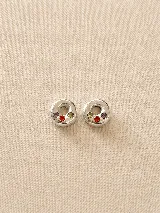 Par de dijes tipo aros en plata con tres zirconias incrustadas de colores rojo, verde y violeta. Diseño artesanal de forma circular irregular.