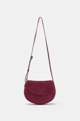 Bolso bandolera de piel de ante color bordó, con solapa curva, cierre de clip metálico y correa larga ajustable.