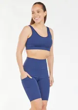 Calza biker deportiva de compresión color azul marino, con cintura alta, recortes y bolsillos laterales.