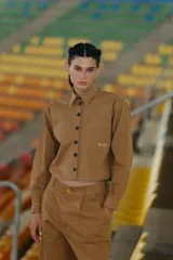 Pantalón camel de gabardina elastizada, corte sastrero, tiro bajo, con bolsillos delanteros, botón metálico y tajo en el lateral interno.