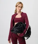 Bolso maleta grande de color negro, marca Satinato, confeccionado en mezcla de poliuretano y poliéster. Cuenta con abertura por cremallera con cierre contrastante, asas de mano, correa larga ajustable y soporte en la base inferior.