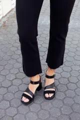 Sandalias negras de cuero con dos tiras, una de cuero liso y otra de charol con estampado animal print. Tienen hebilla metálica plateada y taco bloque.