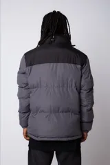 Campera puffer de diseño bicolor, con cuerpo en tono beige y canesú superior en color negro. Presenta cuello alto, cierre frontal completo y puños elásticos.