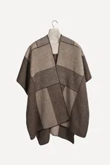 Ruana tejida con diseño de bloques en tonos tierra y beige, con cuello en V y terminación de crochet artesanal.