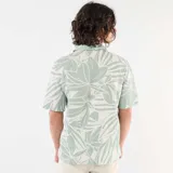Camisa de manga corta con estampado de hojas en tonos verdes y blancos, cuello tipo campana y cierre frontal de botones.