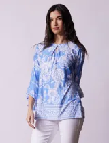 Blusa color salmón con estampado floral blanco, cuello redondo con abertura y mangas 3/4 acampanadas.