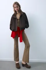 Pantalón de corte flare confeccionado en mezcla de algodón con efecto lavado. Presenta tiro medio, cintura elástica y detalles de tachas y aplicaciones bordadas en el bajo de las piernas.