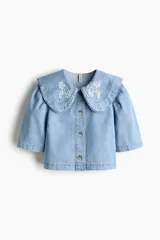 Blusa corta de denim de algodón con cuello Peter Pan bordado, mangas cortas abullonadas y cierre frontal con botones.
