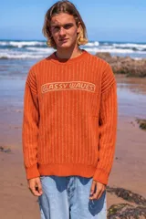 Buzo de tejido de punto acanalado en color naranja, con cuello redondo y estampa frontal con la frase 'GLASSY WAVES' en color crema.