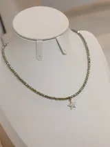 Collar de cristales facetados en tonos verdosos con un dije colgante en forma de estrella con baño en oro y incrustaciones de circonia.