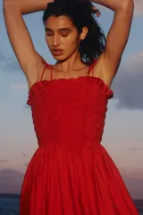 Vestido midi rojo en mezcla de viscosa, con cuerpo fruncido tipo nido de abeja, escote recto, tirantes finos ajustables con moñas y falda amplia con vuelo.