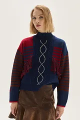 Polera de tejido de punto con diseño multicolor que combina rayas horizontales en tonos azul y bordó, flecos decorativos en el frente y un bordado central en forma de trenza. Presenta cuello semi polera, mangas largas y puños acanalados.