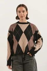 Sweater de tejido bremer con diseño de rombos en tonos negro, beige y marrón. Presenta cuello redondo, mangas largas y un corte holgado.