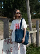 Bolso tipo tote bag confeccionado en denim de color azul oscuro, con costuras reforzadas y diseño espacioso. Cuenta con correas resistentes para llevar al hombro.