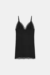 Vestido mini negro con escote en pico y tirantes finos ajustables. Presenta detalles de encaje combinado a tono en el escote y en el ruedo.
