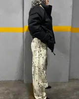 Pantalón de jean color crema con estampado abstracto en tonos marrones, de corte recto y tiro alto.