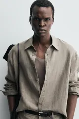 Camisa de manga larga color verde oliva, confeccionada en lino lavado con efecto ligeramente arrugado. Presenta cuello italiano y cierre frontal de botones.