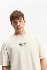 Remera oversize de color beige con gran estampado tipográfico y gráfico en la espalda de la marca Mistral.