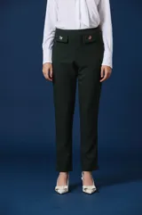Pantalon de vestir color verde oscuro, de corte recto y tiro alto. Presenta dos solapas decorativas en la cintura con apliques de broches metálicos con forma de insectos.