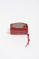 Monedero o tarjetero pequeño de cuero rojo, con cierre de cremallera superior y un tirador de tela a juego. Presenta un bolsillo exterior frontal y el logo de la marca grabado en dorado.