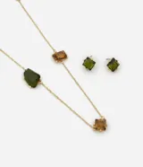 Conjunto de bisutería compuesto por un collar largo de cadena fina con dijes de cristal en tonos verde y ámbar, y un par de aros tipo caravana con dije cuadrado verde. Posee baño en tono dorado.
