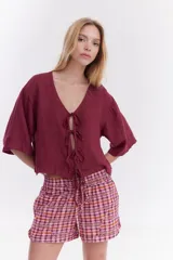 Blusa de lino italiano color beige, de manga corta, con escote en V y cierre frontal mediante lazos o moños.