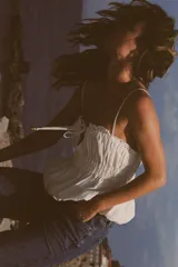 Top blanco de lino con tirantes finos, escote recto, detalle de frunces y cordón ajustable con abalorios.