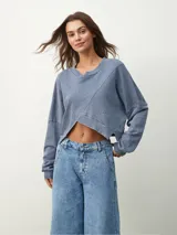 Buzo manga larga color celeste con diseño irregular y corte crop.