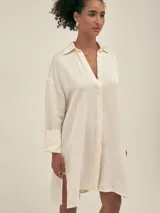 Camisa larga color crema confeccionada en lino-tencel con botones de conchas naturales y bolsillos laterales.