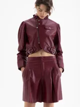 Short de cuero color vino tinto con tablas que generan volumen en las piernas, cintura doble con pespunte y botones forrados en cuero. Cierre lateral.