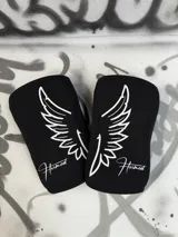 Rodilleras negras de neopreno de 7mm con logo de alas y nombre de la marca en blanco.